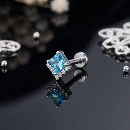Elegancki i subtelny labret, którego ozdobą jest efektowna nakrętka z większą błękitną cyrkonią w kształcie rombu. Nad nią osadzono siedem drobnych, białych cyrkonii