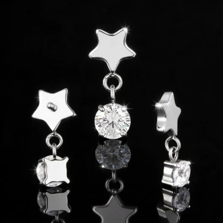 Labret do piercingu z delikatnym, wiszącym elementem ozdobnym. Star Crystal Dangle łączy niewielką gwiazdkę z geometrycznym szlifem i subtelnie zwisającą białą cyrkonię, tworząc lekką, biżuteryjną kompozycję.