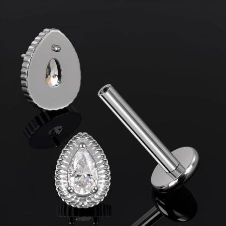 Labret do piercingu z ozdobnym topem w kształcie gruszki, ozdobionym białą cyrkonią osadzoną wewnątrz dekoracyjnej oprawy o karbowanym wykończeniu.